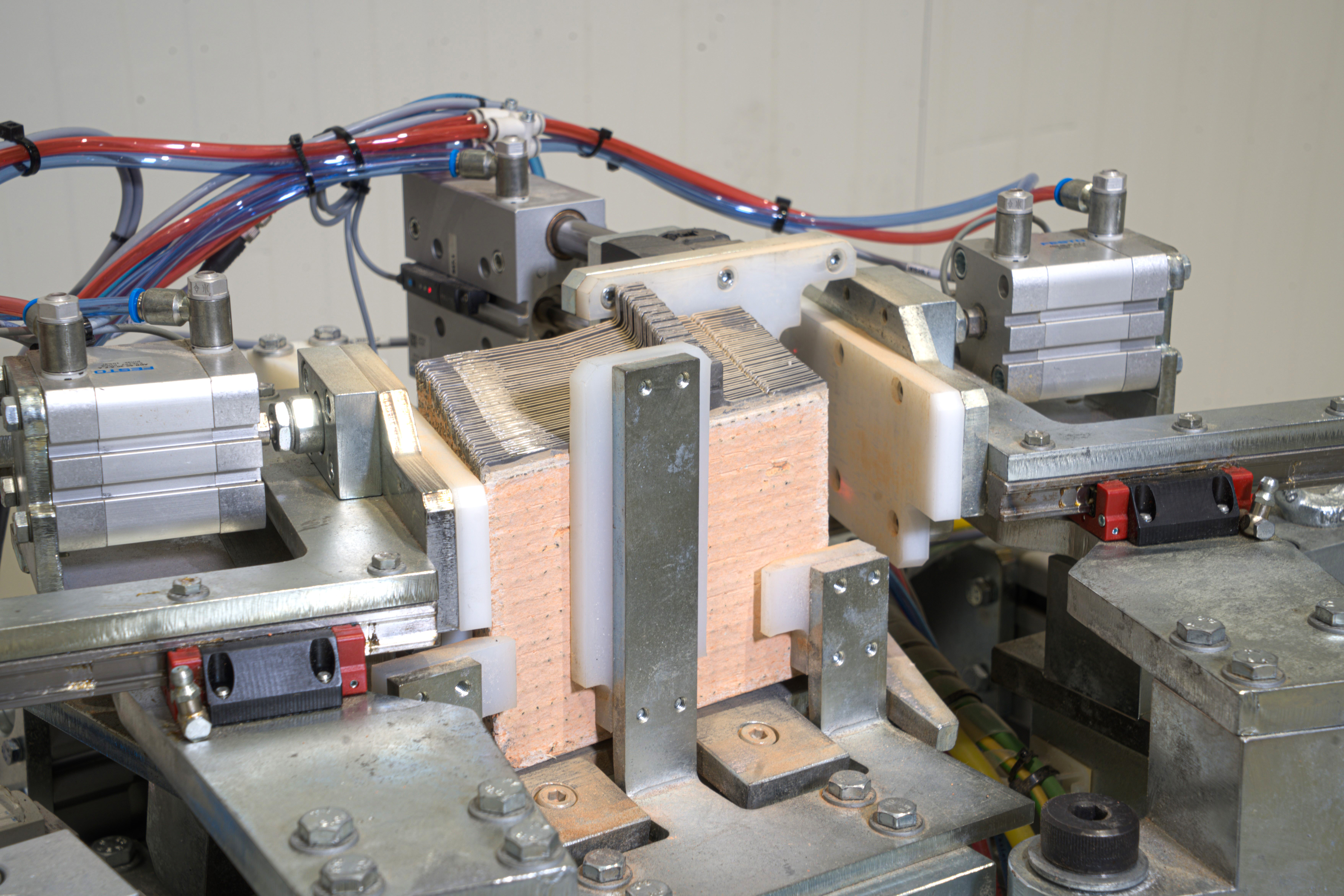 A machine component with metal and ceramic parts, featuring hydraulic and electrical connections, used in industrial manufacturing processes for precision and durability.
