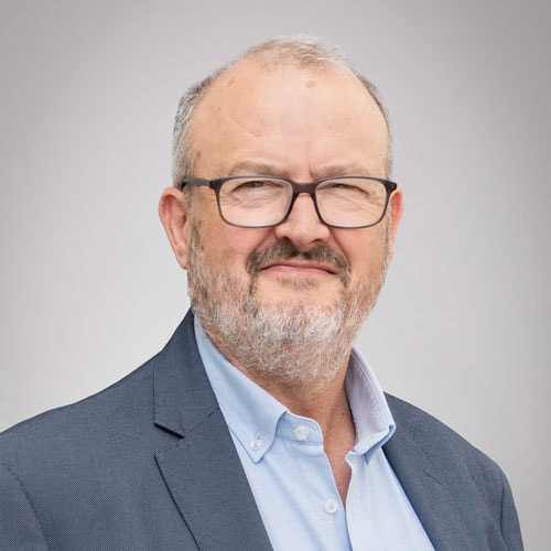 Experienced professional with glasses and a beard, wearing a suit and light blue shirt, representing Rosendahl Nextrom's innovative solutions in the industry.